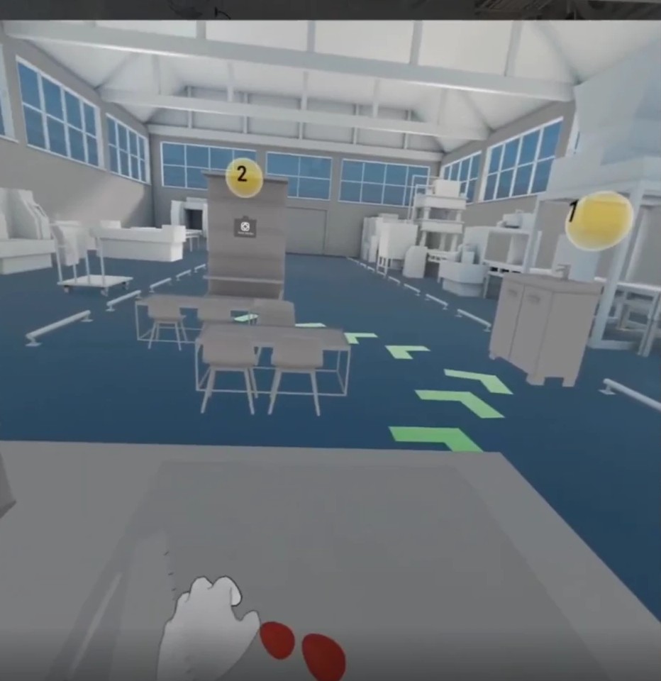 First person view in the makerspace with green arrows across the floor, numbered markers over two destinations, and an injured hand in the foreground